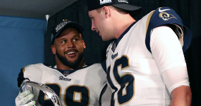 Rams defensive tackle Aaron Donald (99) celebrates in the locker room with the trophy and quarterback Jared Goff (16) after a victory in the NFC Championship game.