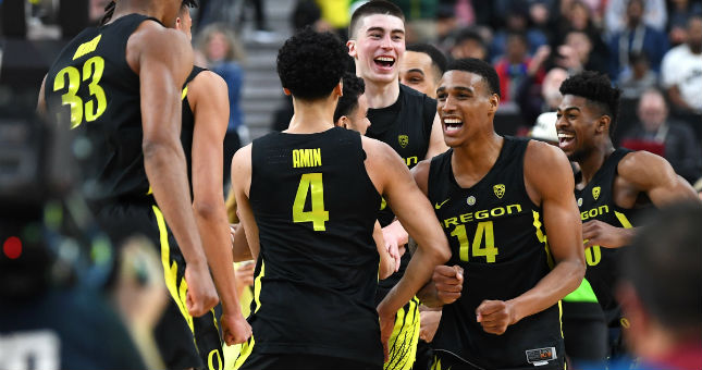 Oregon players rush the floor after defeating Washington 68-48 to win the Pac-12 conference tournament final.