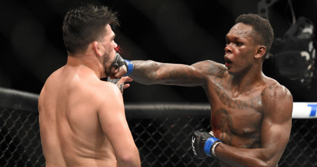 Israel Adesanya (blue gloves) fights Kelvin Gastelum during UFC 236 at State Farm Arena.