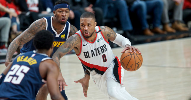 Trail Blazers guard Damian Lillard (0) dribbles past Nuggets forward Torrey Craig.